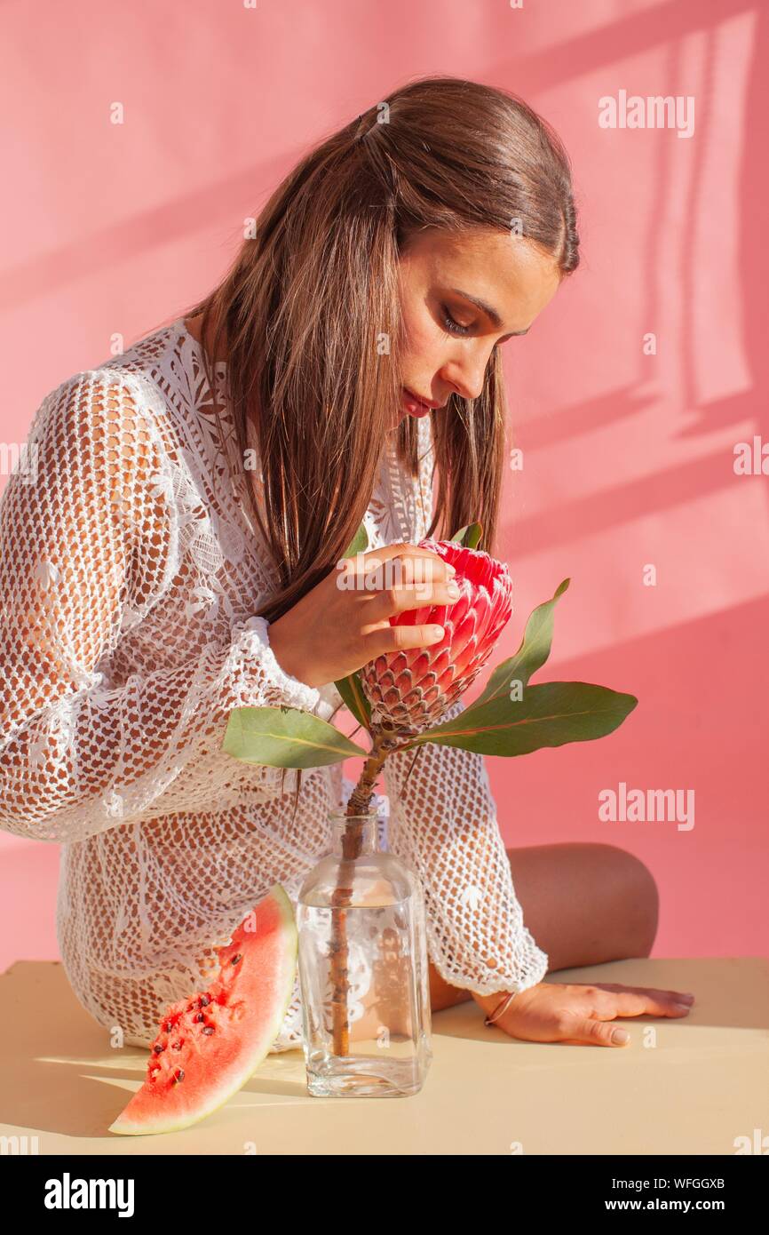 Donna seduta su un tavolo toccando un protea fiore Foto Stock