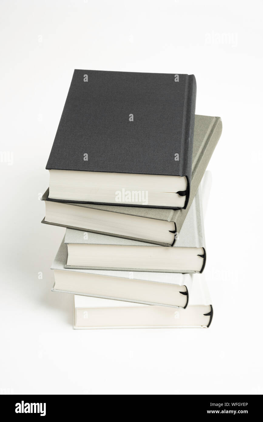 Un disarrayed pila di cinque panno monocromatica-libri rilegati impostato su sfondo bianco. Foto Stock
