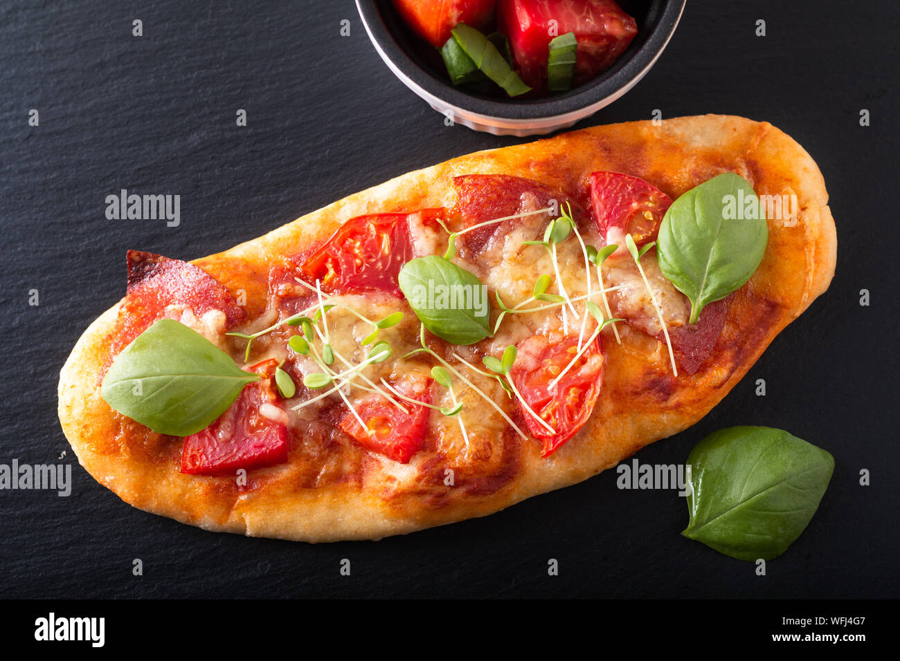 Concetto di cibo organico in casa la pizza con pomodoro, basilico e prosciutto con spazio di copia Foto Stock