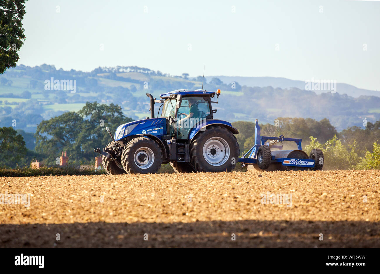Agricoltore che utilizza un terreno agricolo arato e arato di recente con un trattore New Holland nella campagna gallese vicino a Ruthin a Clwyd nel Galles del Nord Foto Stock