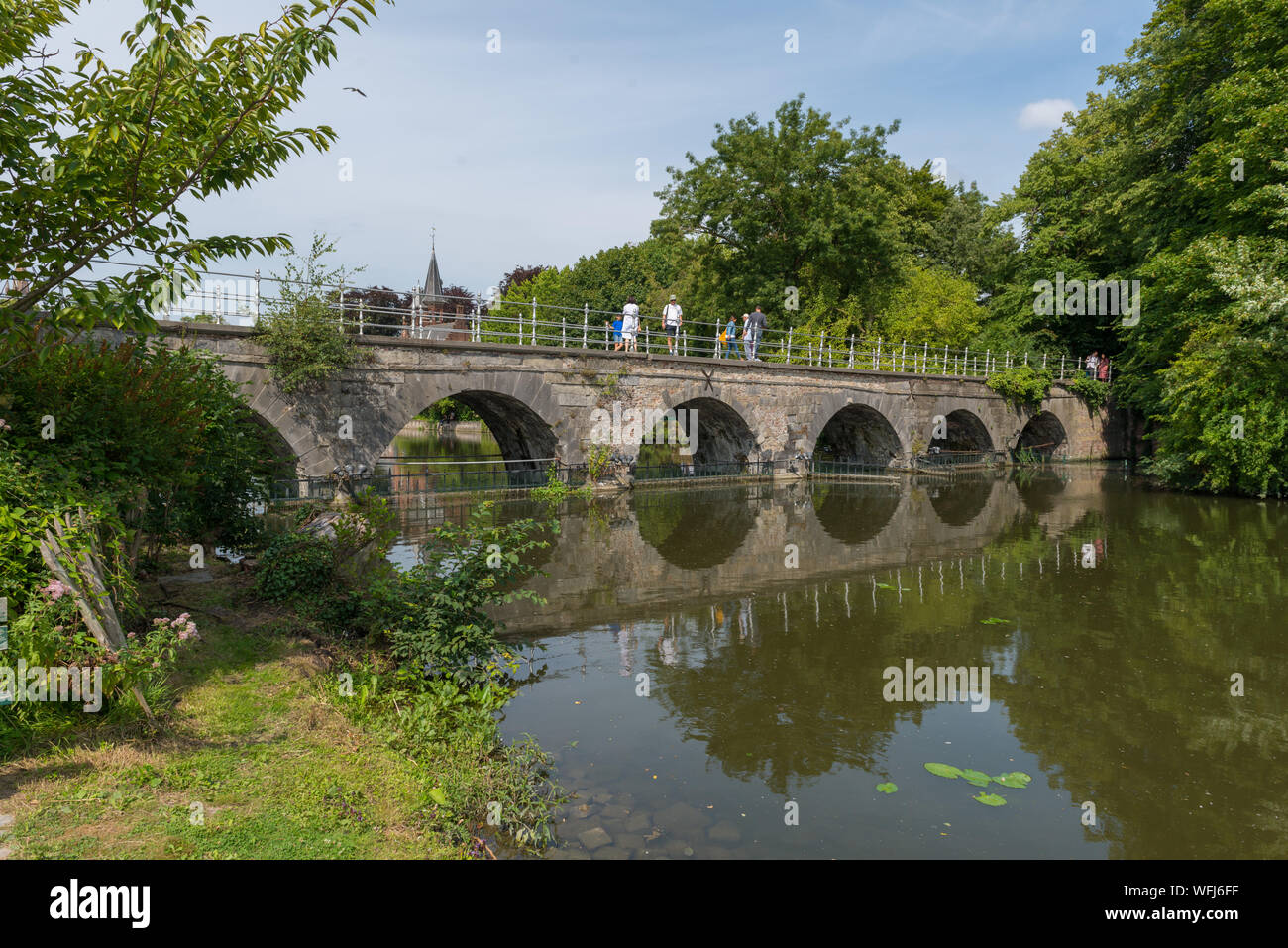 La gente sul ponte sopra il Minnewater (Lago di amore) in il Minnewaterpark a Bruges, Belgio Foto Stock