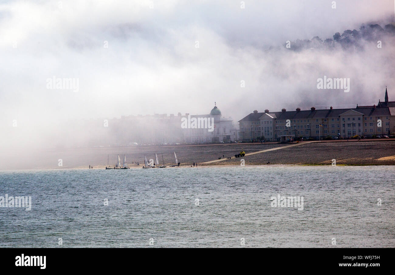 La nebbia del mare di nebbia in rotolamento dal mare sul lungomare e la spiaggia del Galles del nord della stazione balneare di Llandudno Foto Stock