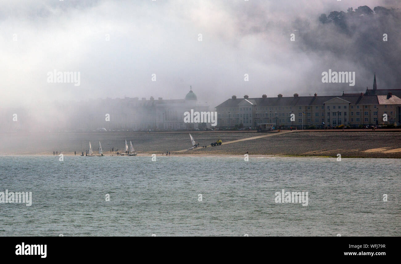 La nebbia del mare di nebbia in rotolamento dal mare sul lungomare e la spiaggia del Galles del nord della stazione balneare di Llandudno Foto Stock