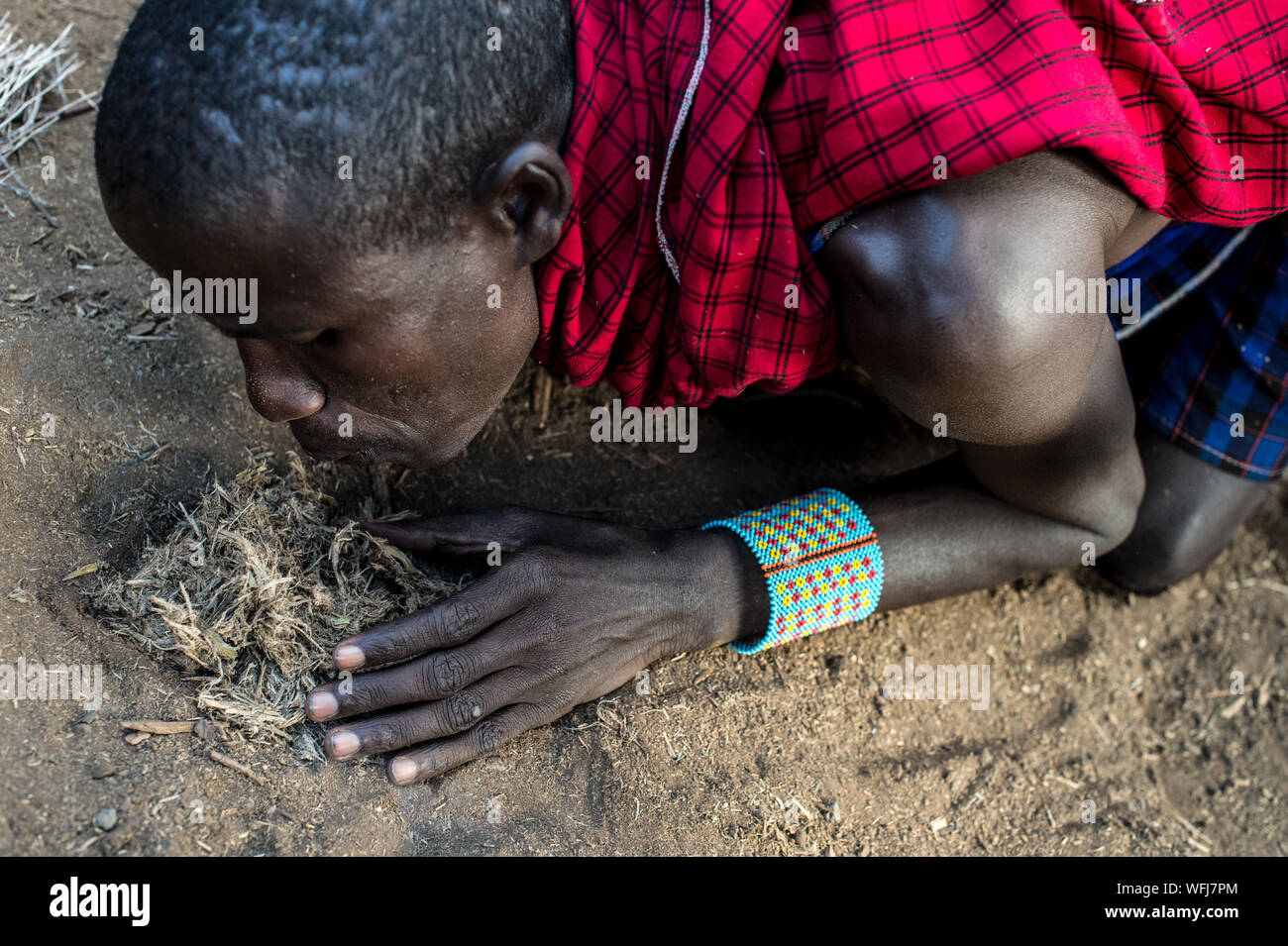 Tribù Masai man start incendio con bastoni di legno. Villaggio Tradizionale all'interno di vil Amboseli National Park, Kenya, Africa Foto Stock