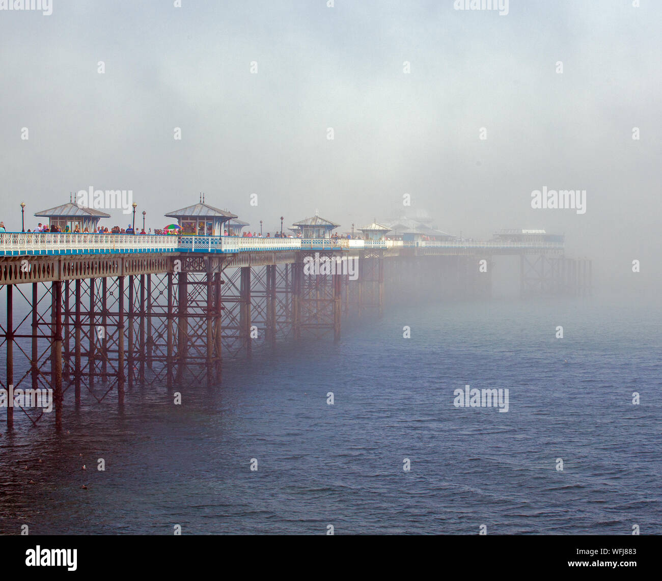 La nebbia del mare di nebbia in rotolamento dal mare oltre il molo del Galles del nord della stazione balneare di Llandudno Foto Stock