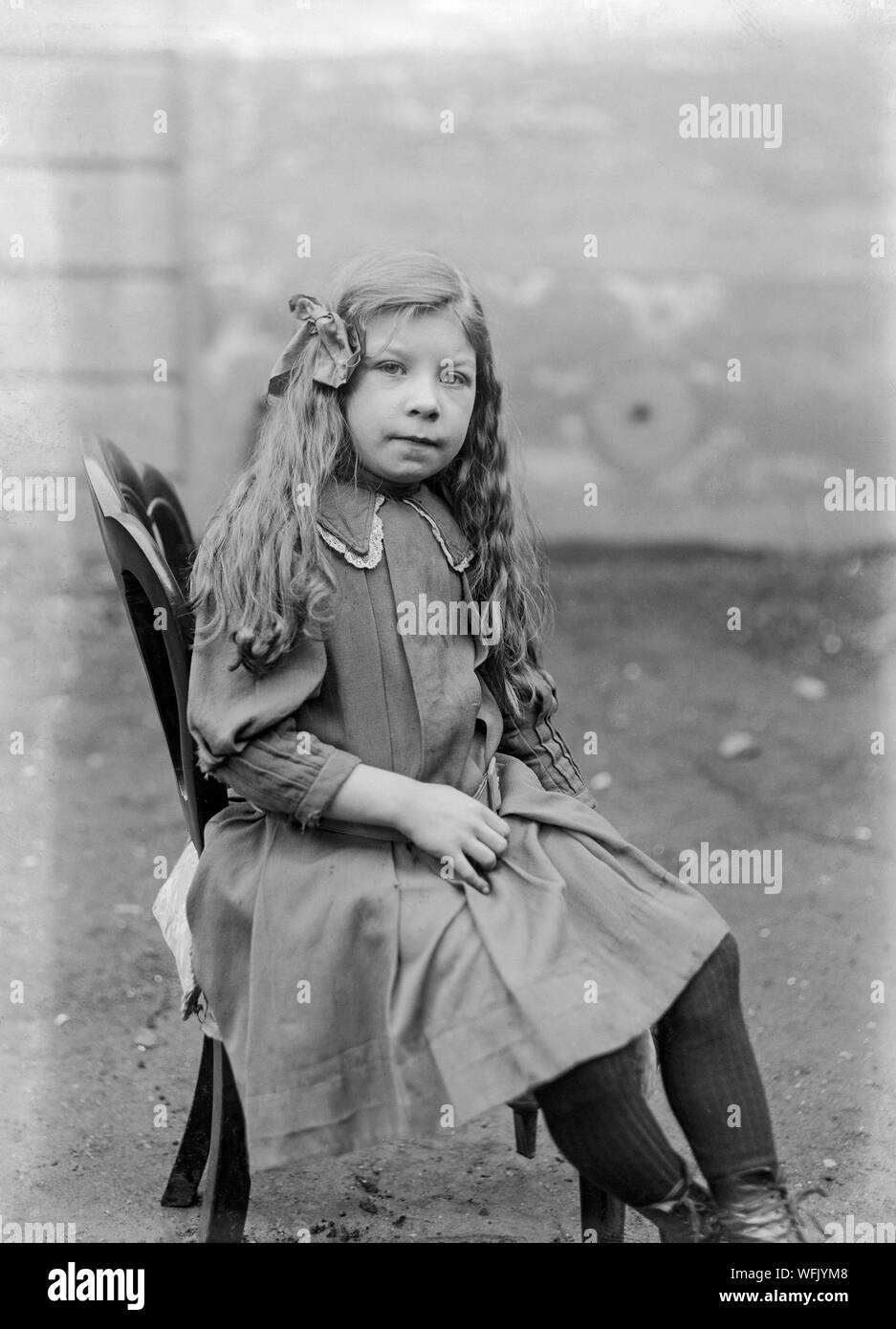 Una vendemmia tardiva o vittoriano inizio Edwardian fotografia in bianco e nero che mostra una ragazza con i capelli lunghi e in una posa seduto in uno studio fotografico. Foto Stock