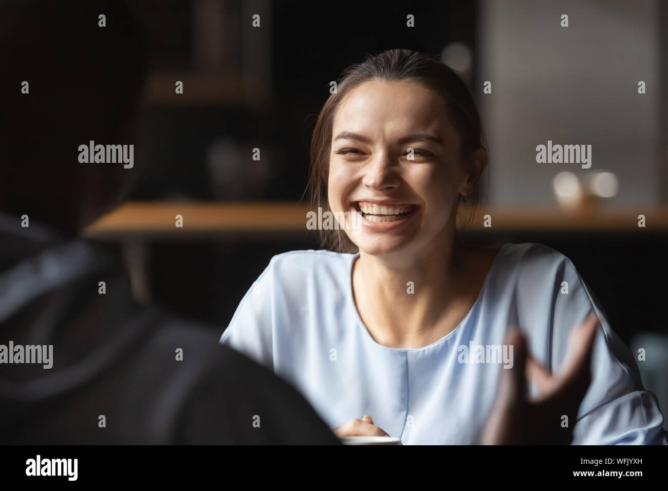 Felice giovane donna caucasica ridendo incontro ragazzo africano in cafe Foto Stock
