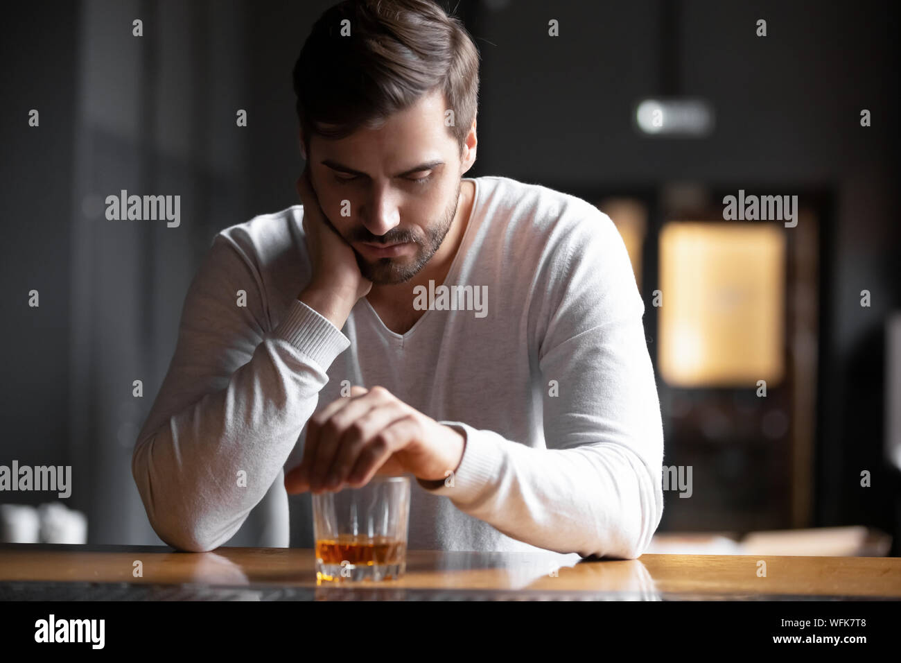 Turbare l uomo bevitore seduta alcolica con vetro di bere whisky da solo Foto Stock