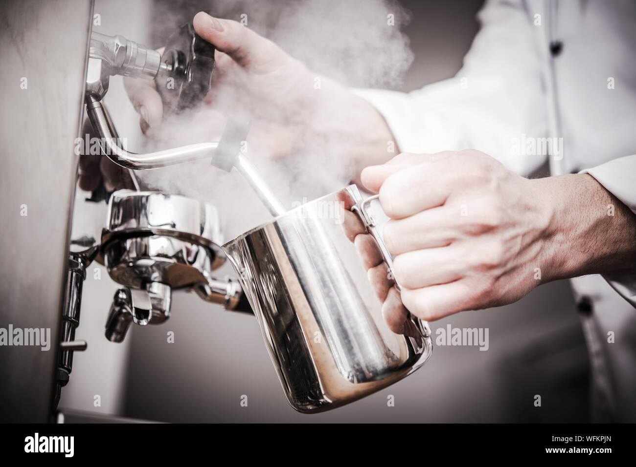 Immagine ritagliata del barista latte fumante al Cafe Foto Stock