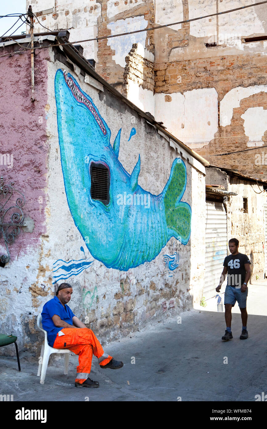 PALERMO : abitanti di un povero neighboorhood in un vicolo con un murale di una balena. Foto Stock