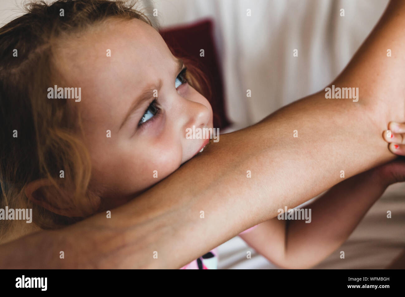 Femmina Toddler mordere il braccio della madre. Bambini affrontano le fasi di crescita, compresi morso. Foto Stock