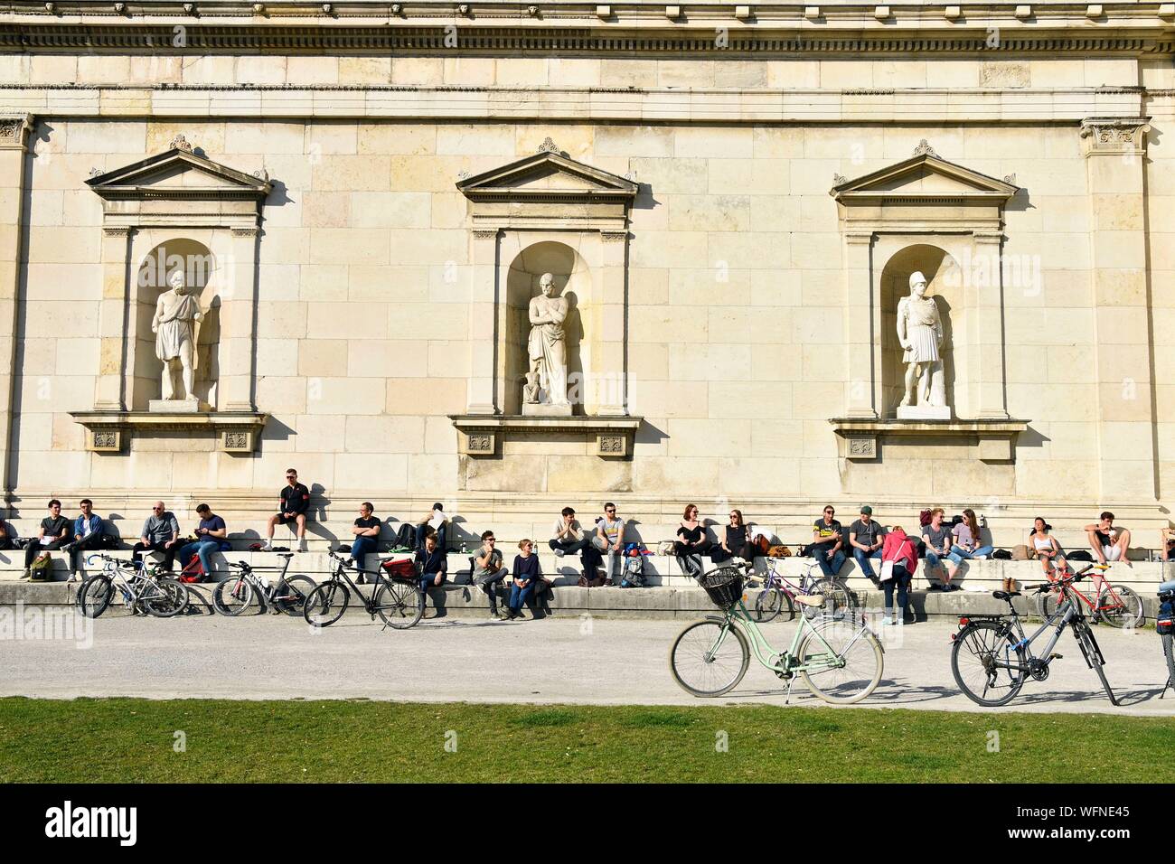 In Germania, in Baviera, Monaco di Baviera, Königsplatz, Glyptothek, museo fondata nel 1830 dal re Luigi I di Baviera per accogliere le sue collezioni di sculture greche e romane, studente lavora appoggiata contro la facciata neoclassica Foto Stock