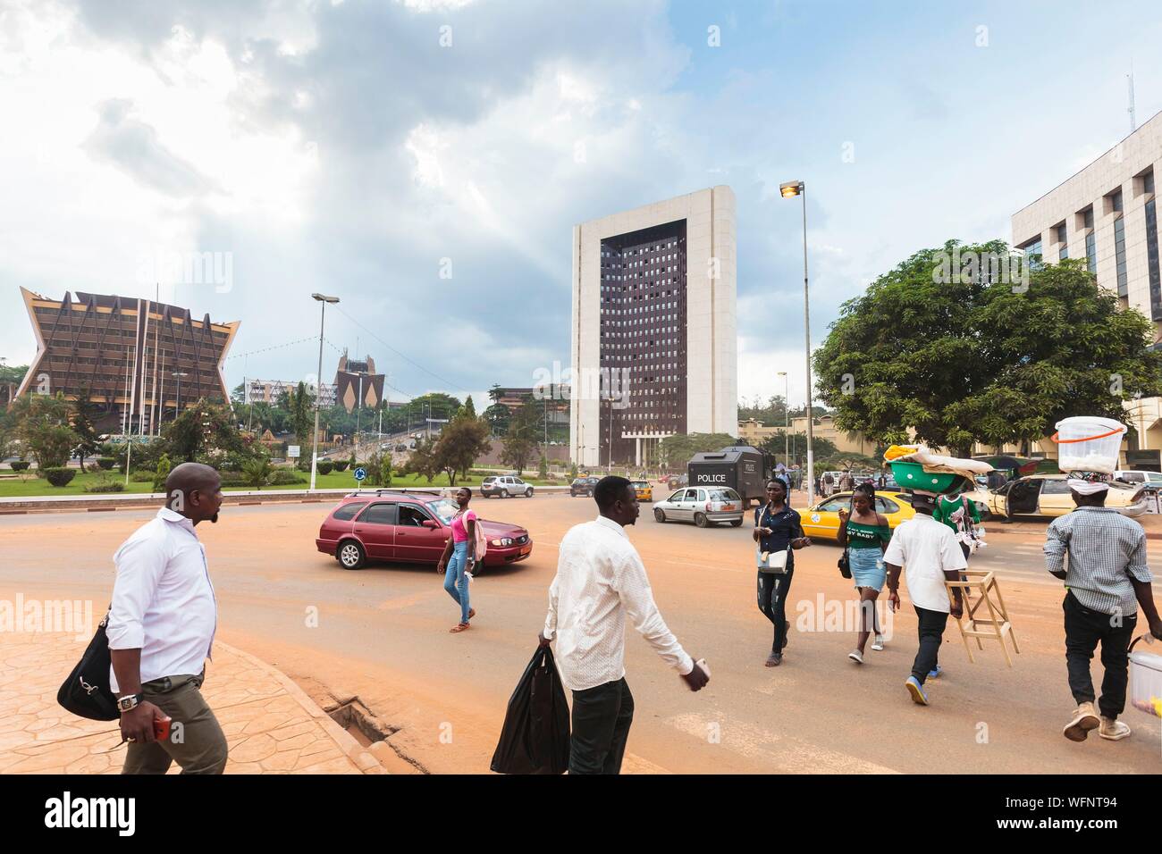 In Camerun, la regione centrale, Dipartimento Mfoundi, Yaoundé, Centro citta', 20 maggio Square, automobili e persone nella parte anteriore del primo ministro dell'ufficio edificio e nella parte anteriore del Ministero per i beni di Stato, indagini e il possesso della terra Foto Stock