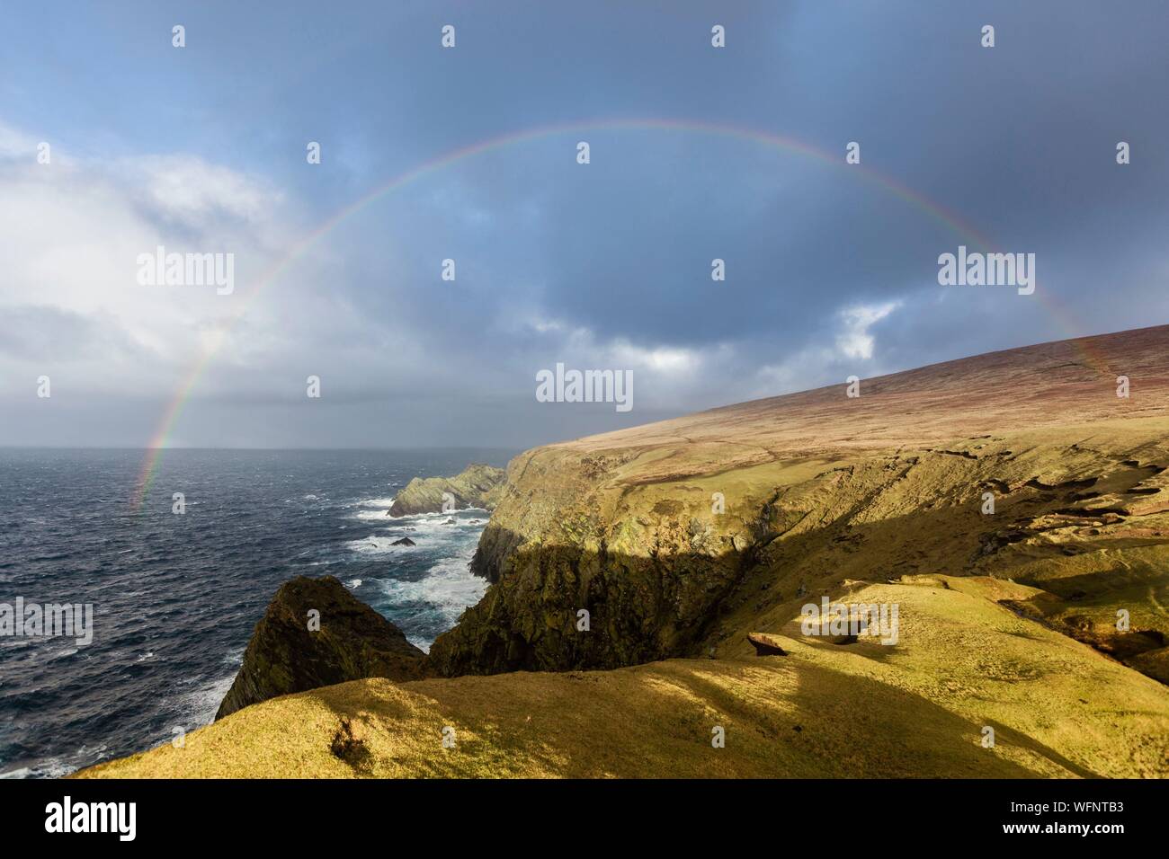 Regno Unito, Scozia, isole Shetland, isola di Unst, Hermaness Riserva Naturale Nazionale, full rainbow che collega la costa rocciosa e il mare Foto Stock