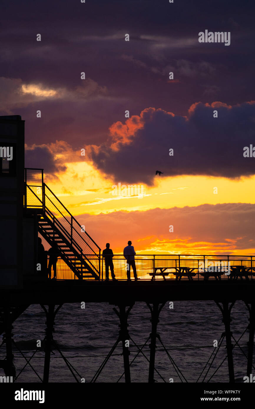 Aberystwyth Wales UK, sabato 31 agosto 2019 persone in piedi sulla Aberystwyth vittoriana molo sul mare si stagliano come guardare l'ultimo tramonto del 2019 estate . Domani, 1 settembre segna il primo giorno di autunno meteorologico. Credito foto Keith Morris / Alamy vivere nuove Foto Stock