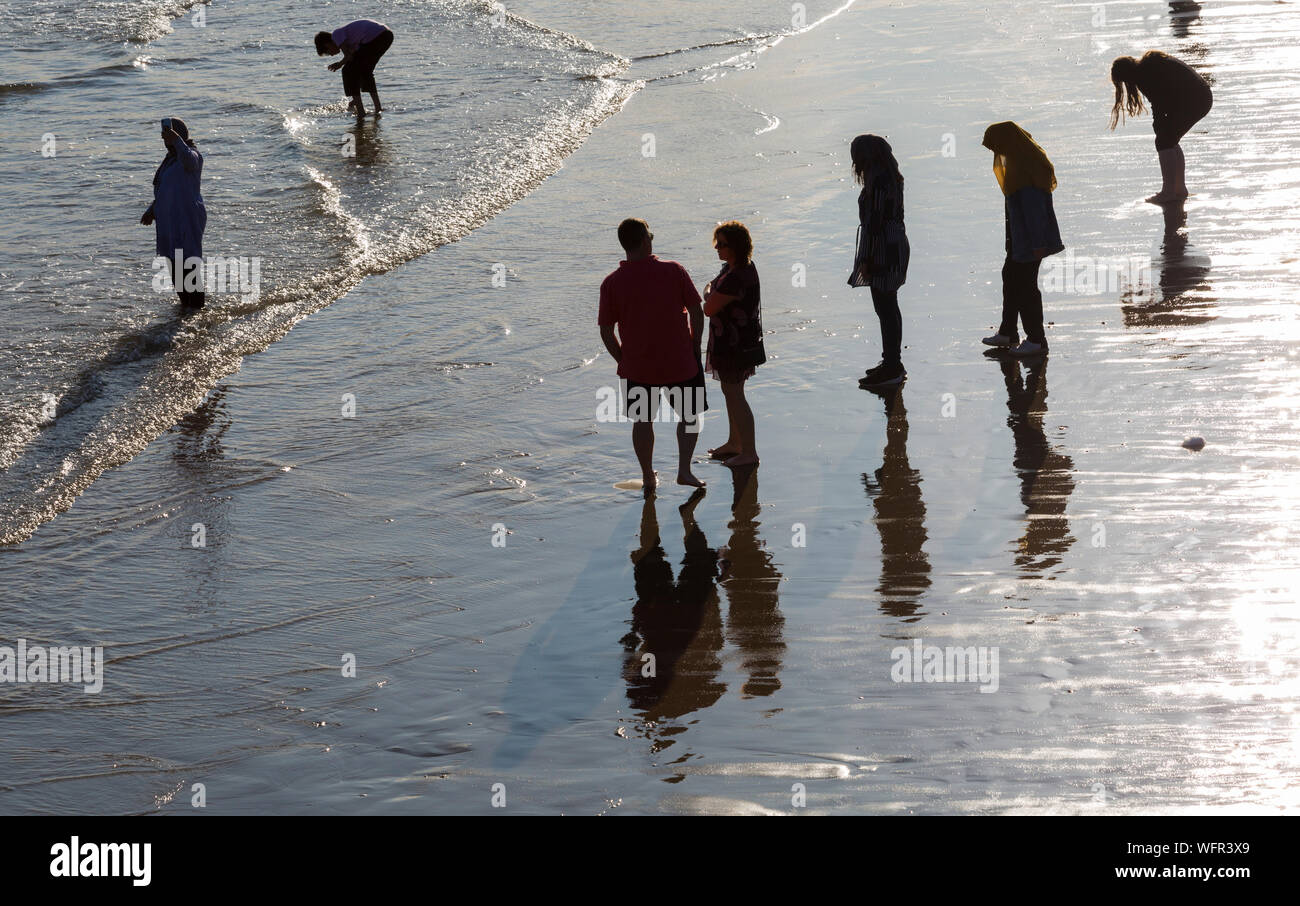 Bournemouth Dorset UK. Il 31 agosto 2019. Regno Unito: meteo visitatori apprezzano i resti del giorno a Bournemouth Beach stagliano figure come il sole scende dopo un giorno misti di meteo - piovoso e umido pomeriggio presto, trasformando in una gloriosa caldo e soleggiato nel pomeriggio e la sera come la folla gregge al mare a Bournemouth Beach per guardare il Bournemouth air festival. Credito: Carolyn Jenkins/Alamy Live News Foto Stock