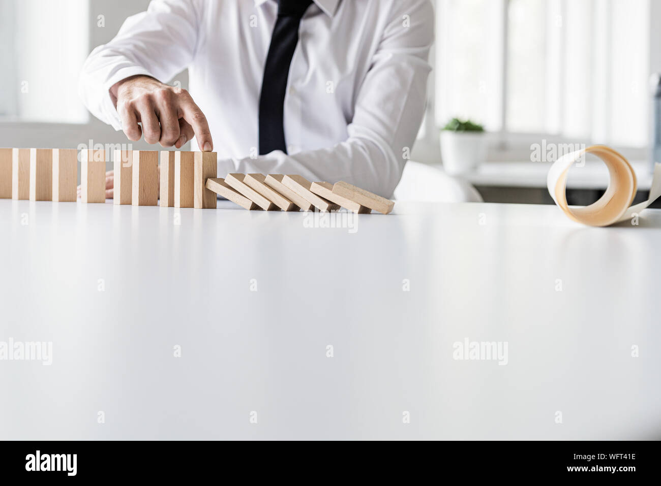 Crisi Business manager seduto alla sua scrivania l'arresto dei dominos collassi con la carta e il piano sulla sua tavola. Foto Stock