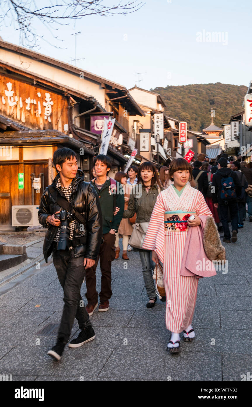 Uno sguardo laterale di un giovane uomo giapponese a una donna moderna vestita con un kimono tradizionale in via Kiyomizu-Zaka a Kyoto durante un festival di primavera. Foto Stock