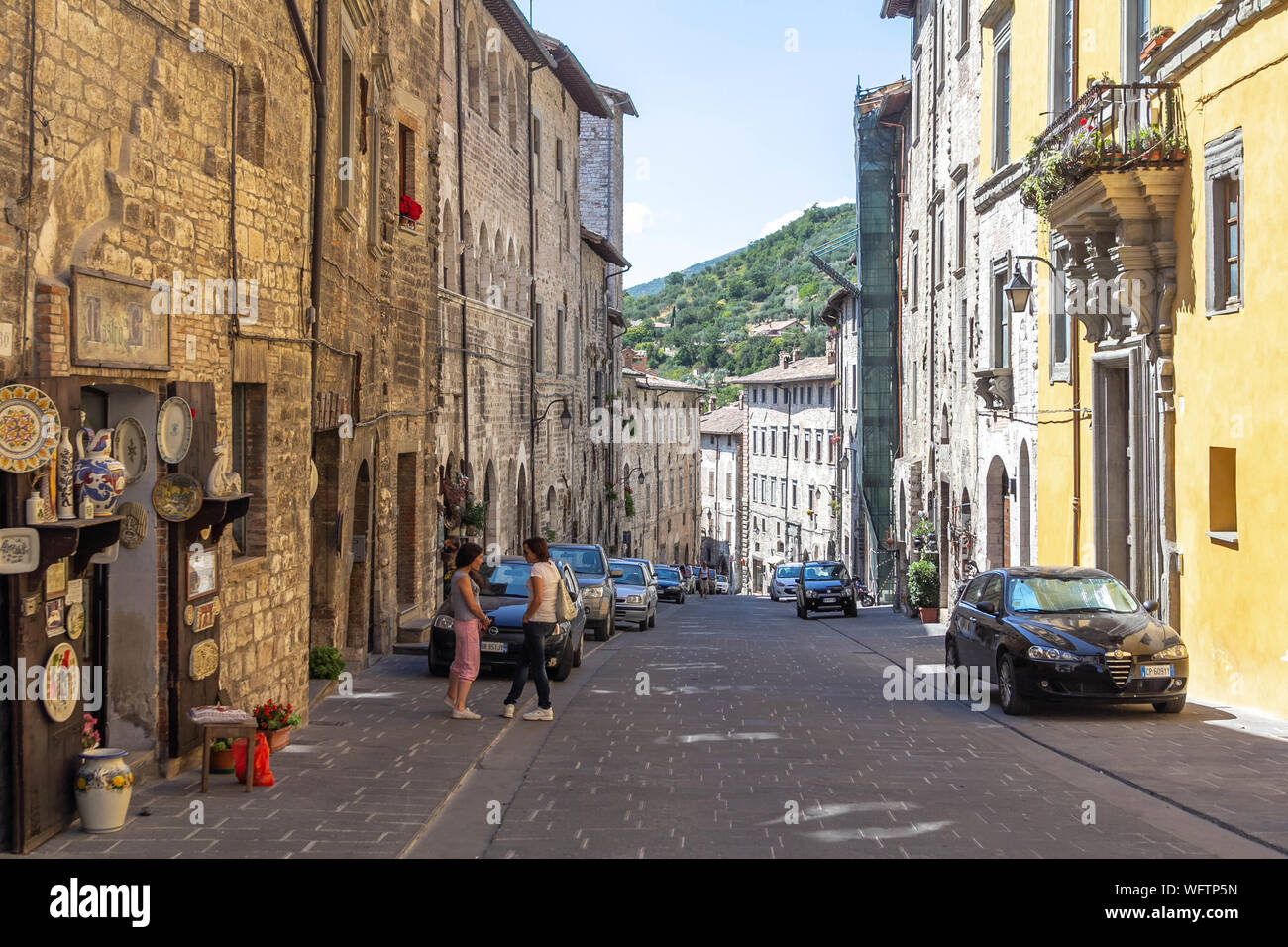 Gubbio, Italia - Luglio 16, 2012: le strade di Gubbio, in Umbria Italia, con un paio di persone e di automobili parcheggiate Foto Stock