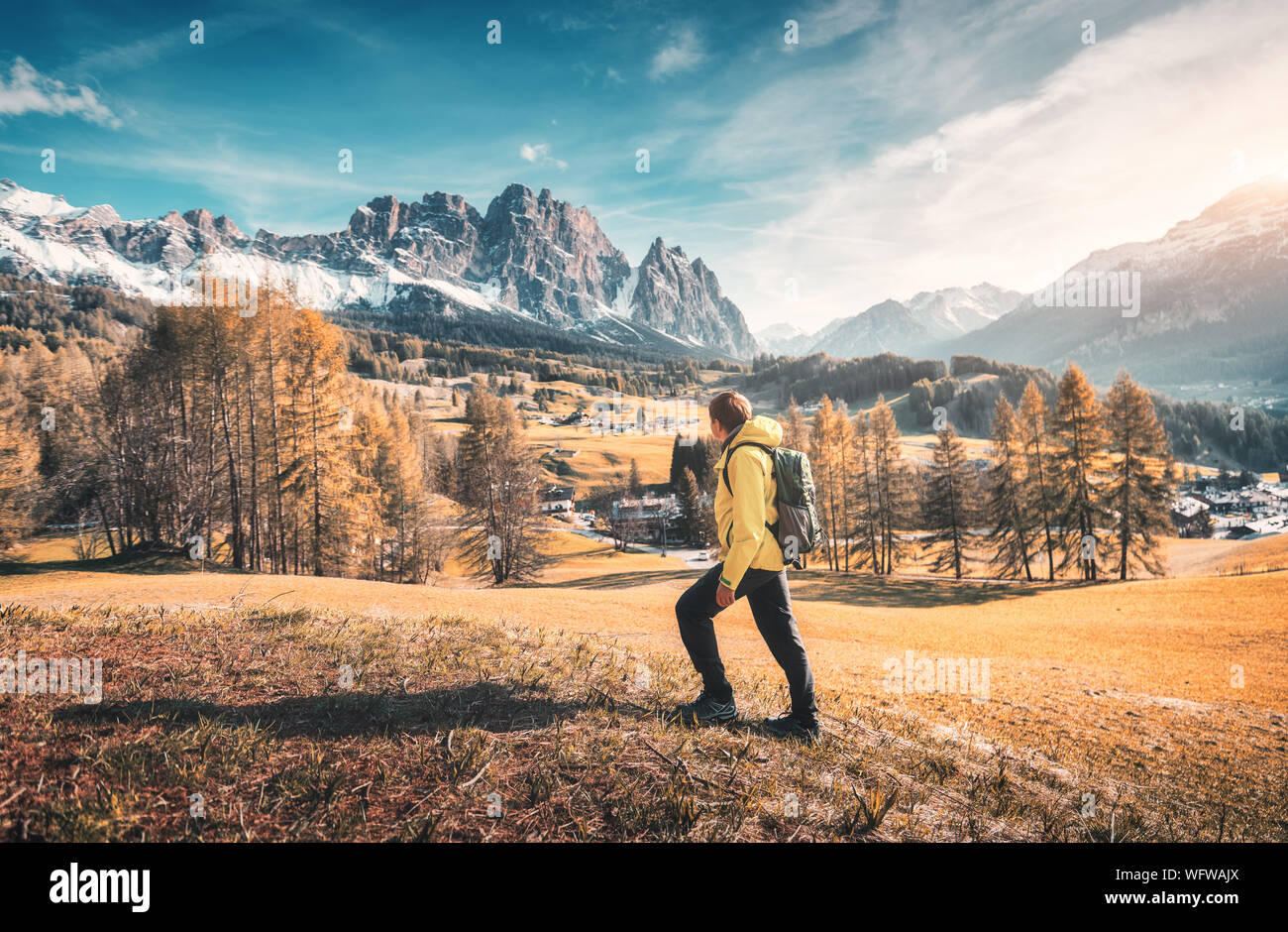 Un giovane uomo con giacca gialla e zaino sta camminando il meado Foto Stock