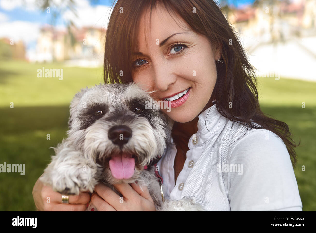 Ritratto di un felice caucasian donna che abbraccia il suo amato cane.Il concetto di amore per gli animali. migliori amici. Cane di razza Schnauzer. giornata di sole Foto Stock