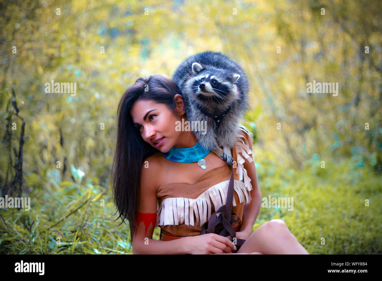 Giovane donna in abiti tradizionali che trasportano Raccoon in foresta Foto Stock