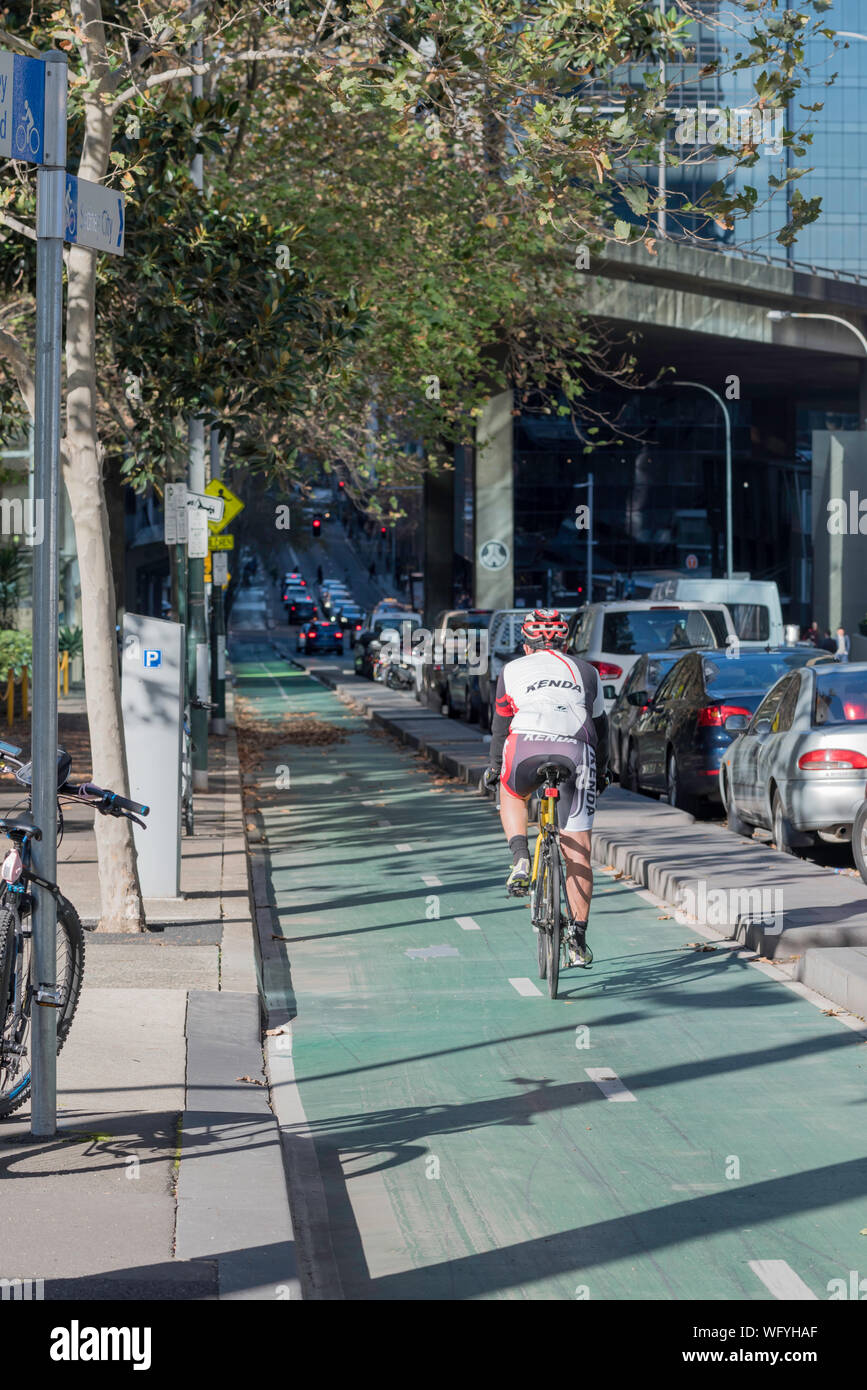 Un maschio adulto ciclista passa in un protetto dedicato pista ciclabile su Kent Street a Sydney in Australia Foto Stock
