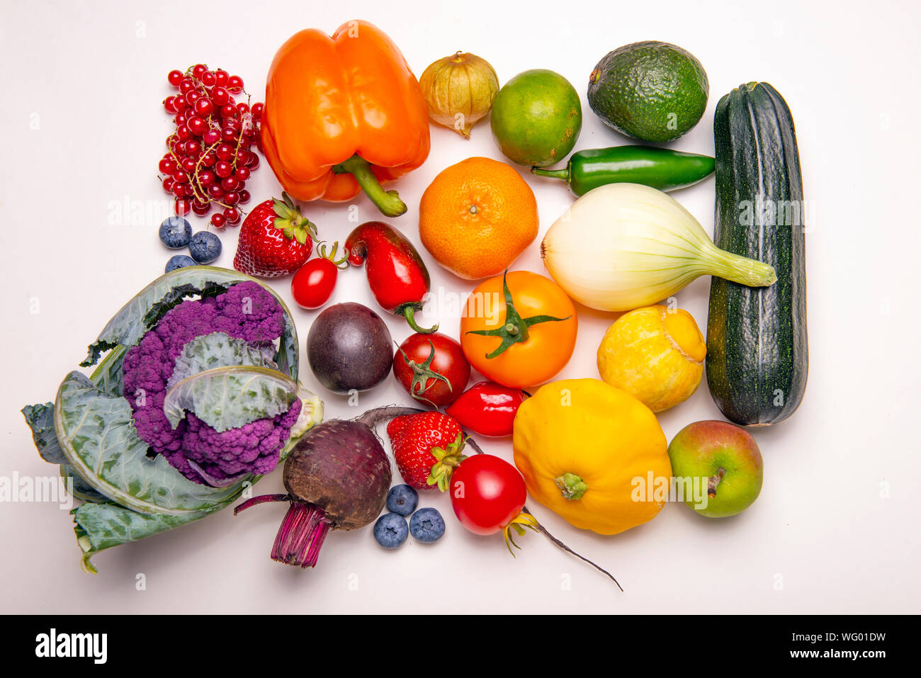 Un assortimento di frutta fresca e verdura disposte in un arcobaleno di pattern a colori su sfondo whiate Foto Stock