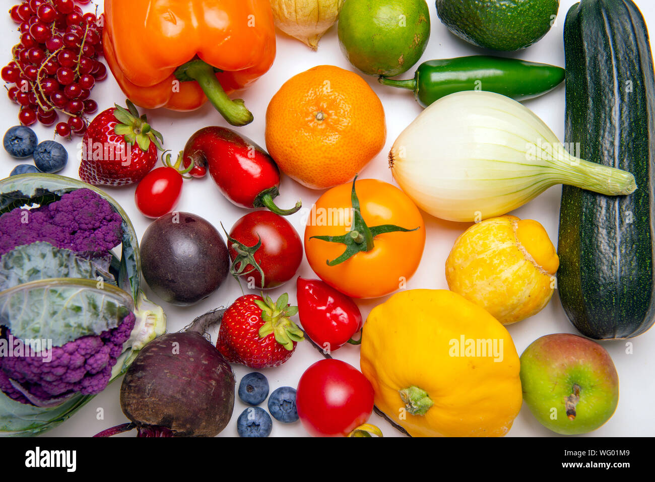 Un assortimento di frutta fresca e verdura disposte in un arcobaleno di pattern a colori su sfondo whiate Foto Stock