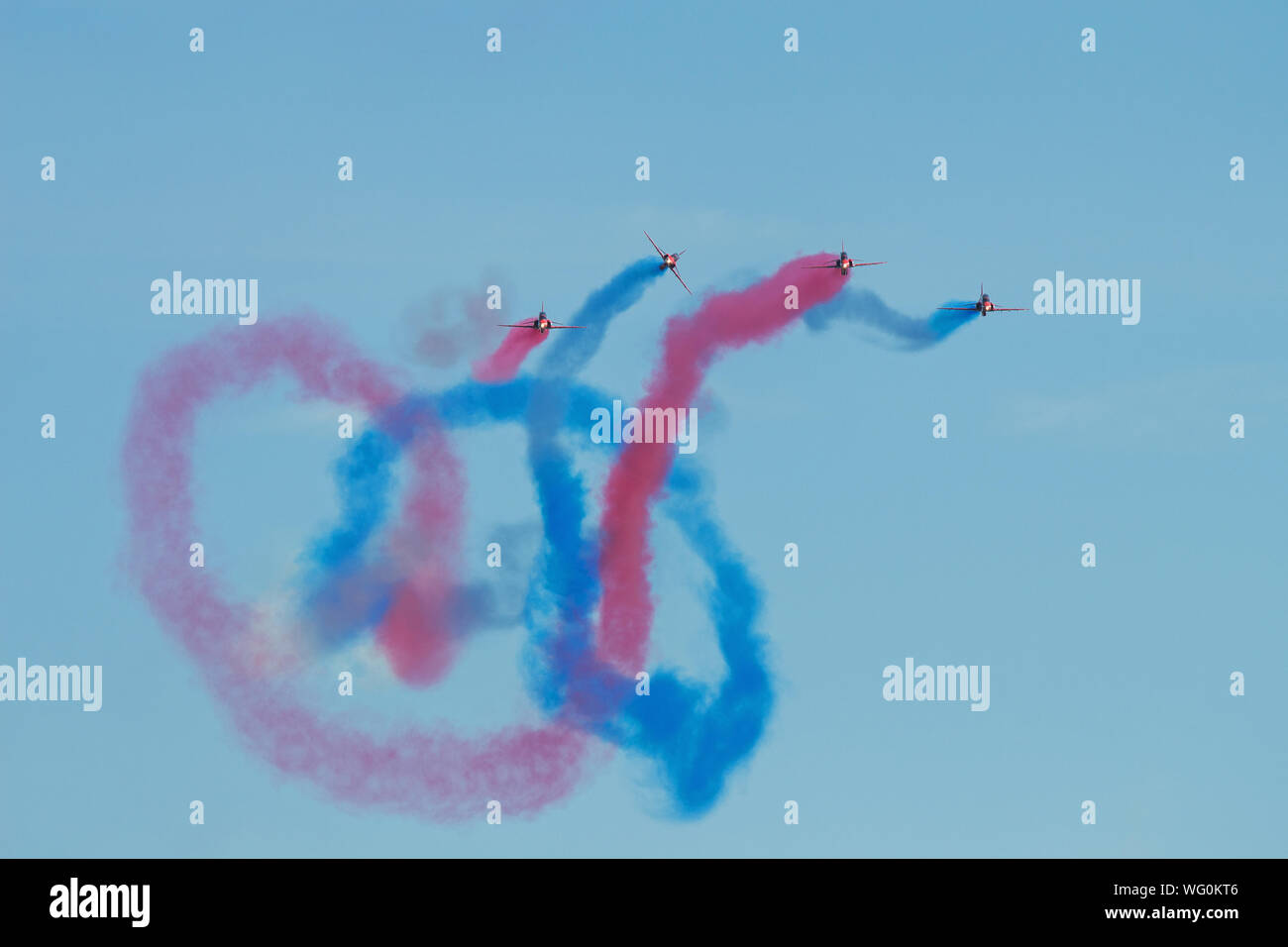 Quattro delle frecce rosse lasciano scie di rosso e di blu fumo intrecciarsi nel cielo nelle loro prestazioni a Eastbourne di Airshow internazionale, 2018. Foto Stock