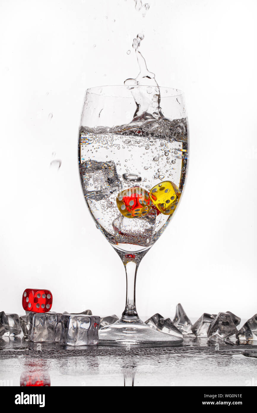 Dadi, cristalli di ghiaccio e un bicchiere di acqua ona backround in vetro Foto Stock