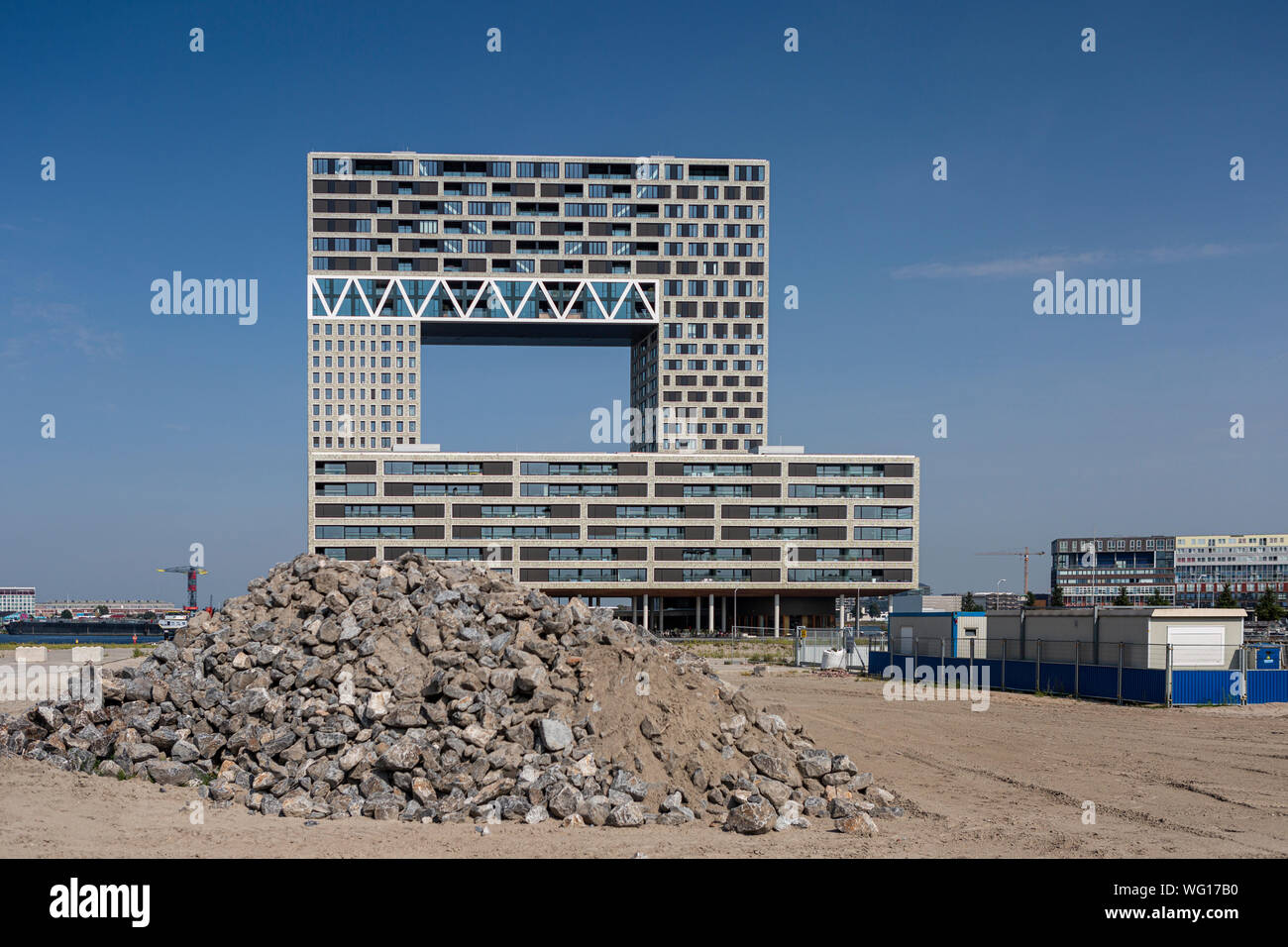 Pila di rocce e di contenitori sul sito di costruzione con recentemente terminato il moderno edificio di appartamenti nel quartiere Houthaven nella parte posteriore Foto Stock