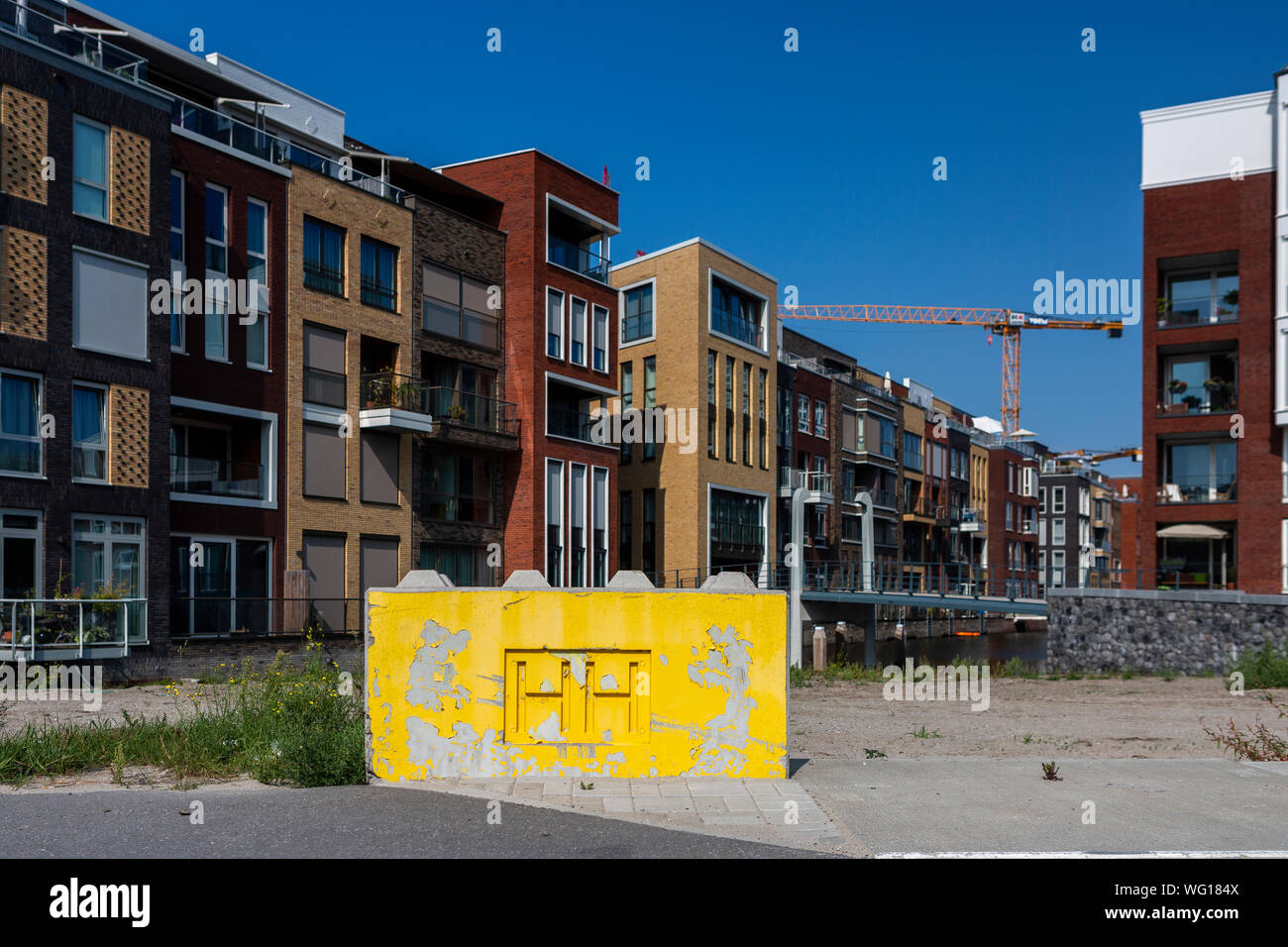 Blocco di cemento dipinto di giallo blocca la strada e come delimitazione della in costruzione Houthaven quartiere con le iniziali di HH Foto Stock
