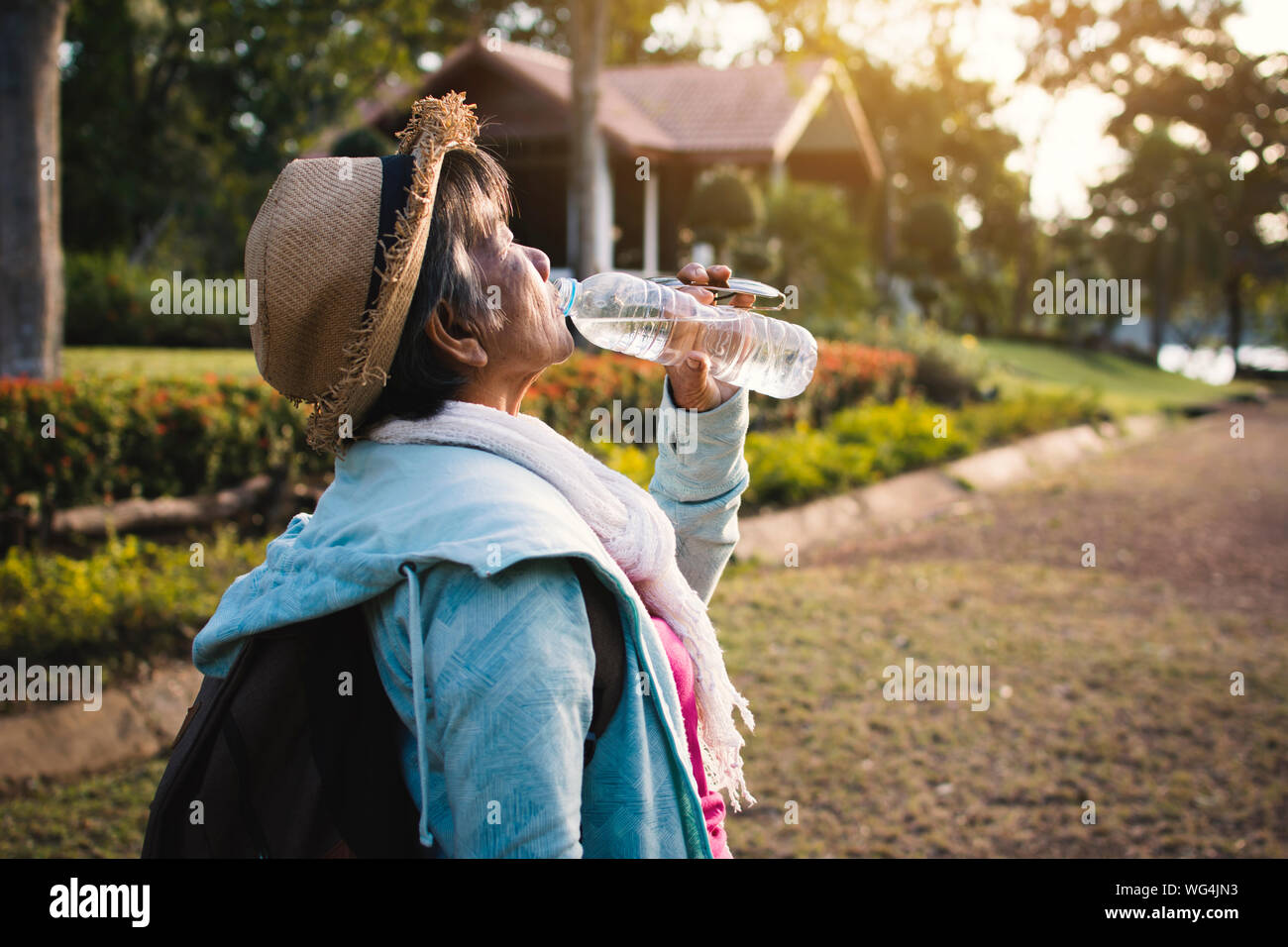 Senior donna acqua potabile mentre in piedi su strada Foto Stock