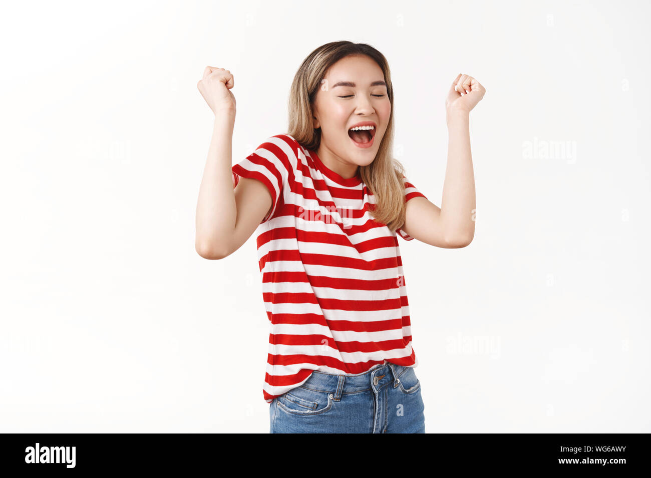 Urrà dolce successo. Allegro silly carino coreano asiatica ragazza bionda alzando i pugni festosa celebrando awesome buone notizie il fortunato vincitore trionfante dancing Foto Stock