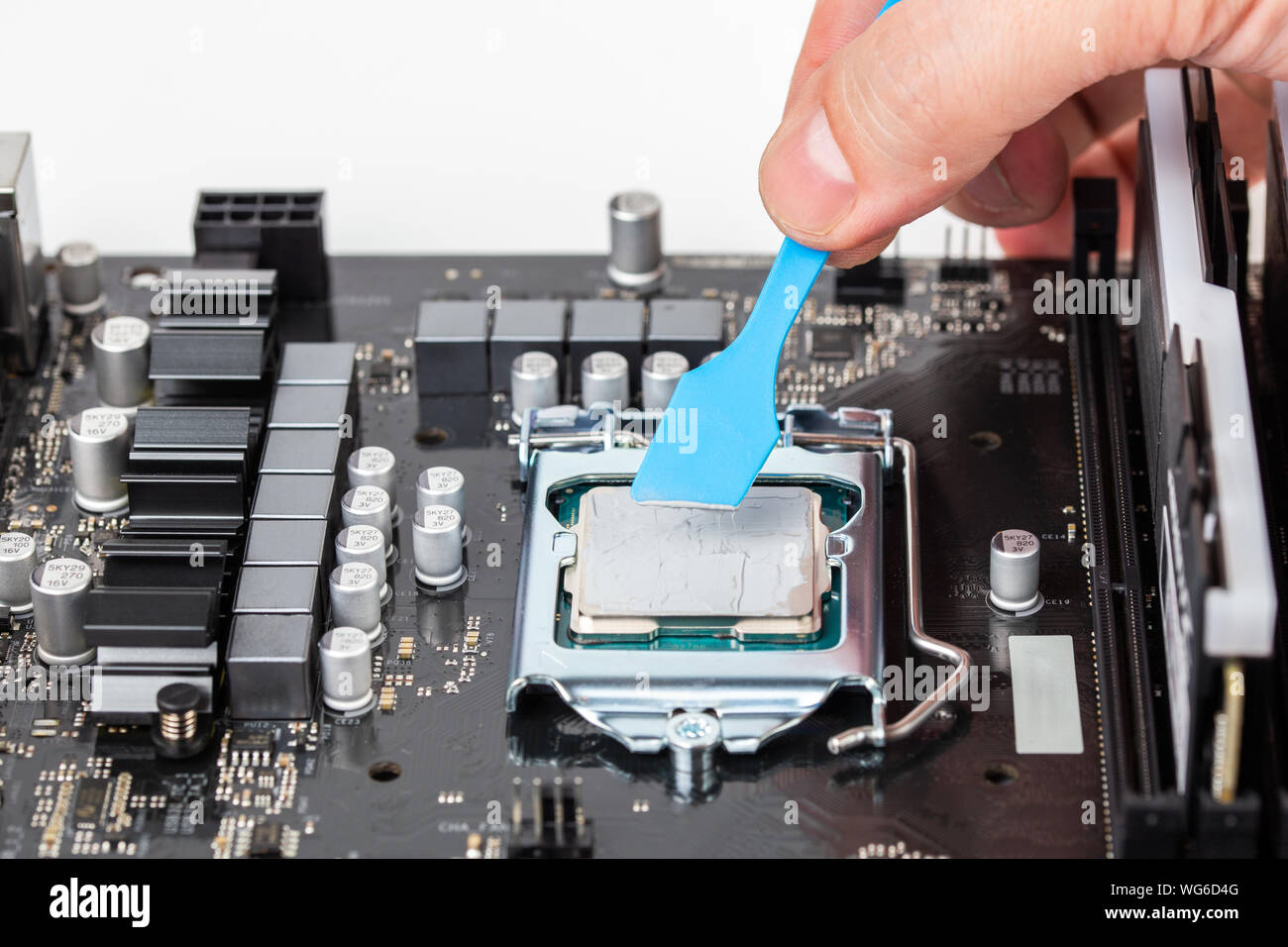 Mano grigia si applica il lubrificante termico sul processore centrale nella scheda madre del PC - closeup con messa a fuoco selettiva e la sfocatura Foto Stock