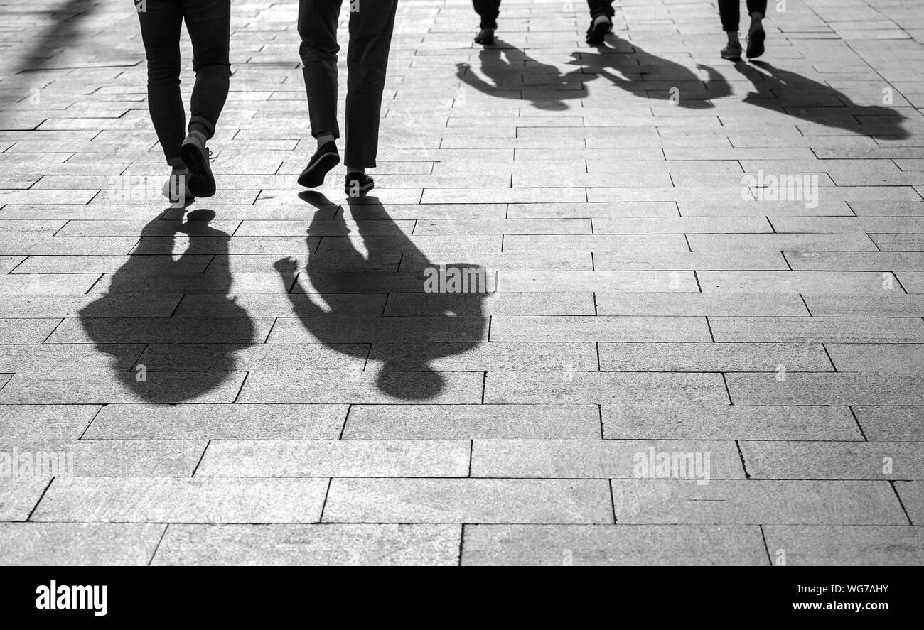 Ombre e sagome di persone, città durante il tramonto, persone a camminare su una strada Foto Stock