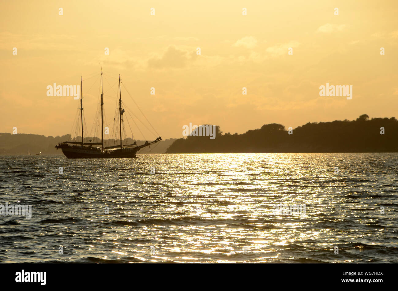 Vecchia nave a vela derive al porto si vede come una silhouette in controluce. Foto Stock