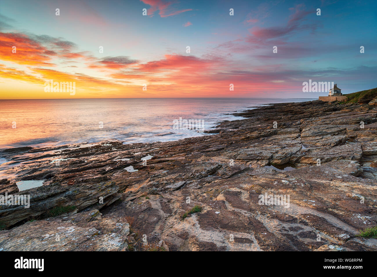 Sunrise sulla spiaggia a Howick sulla costa di Northumberland con la vecchia casa di balneazione a distanza Foto Stock