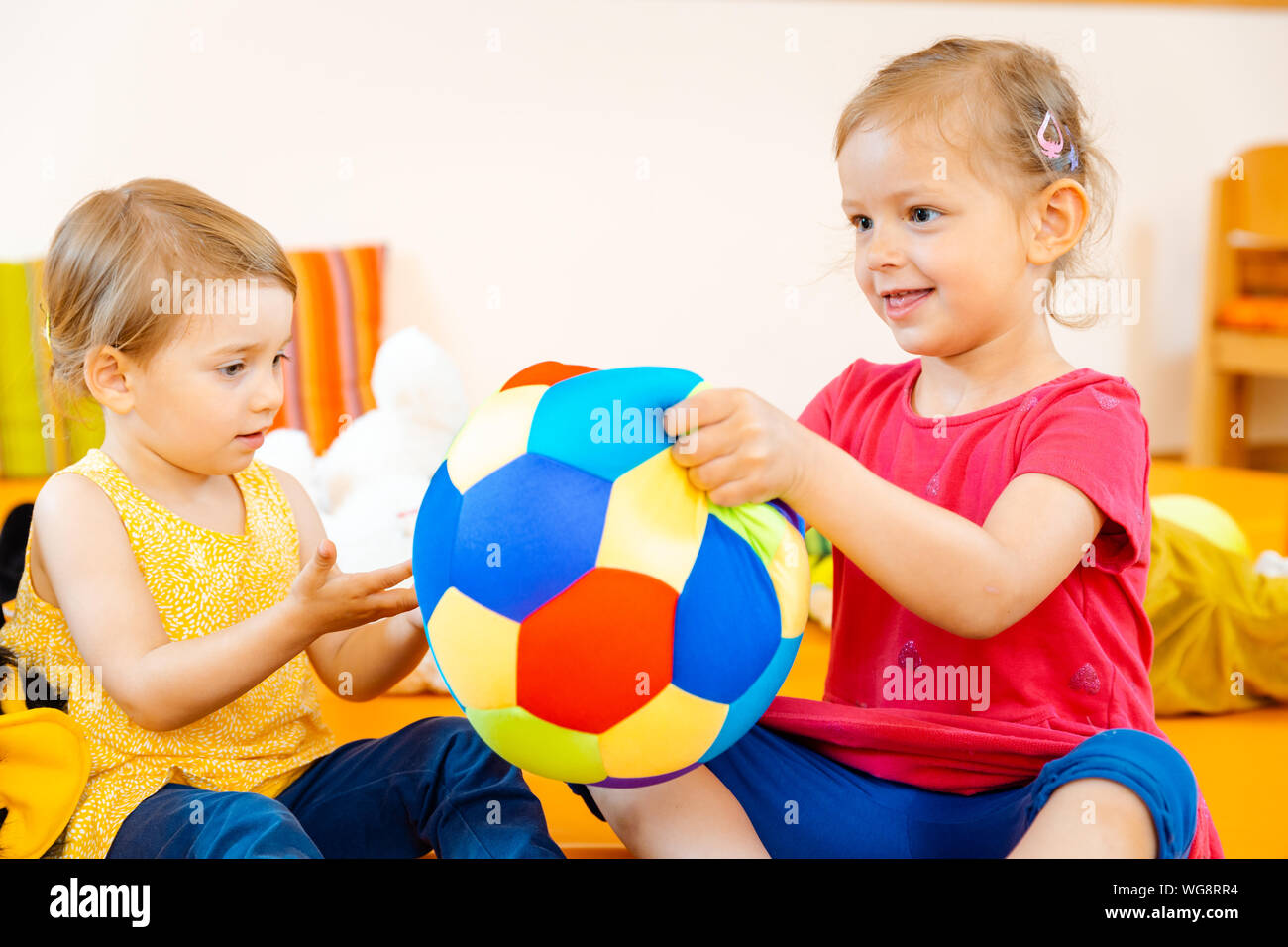 Due ragazze nella scuola di gioco per divertirsi con una sfera Foto Stock