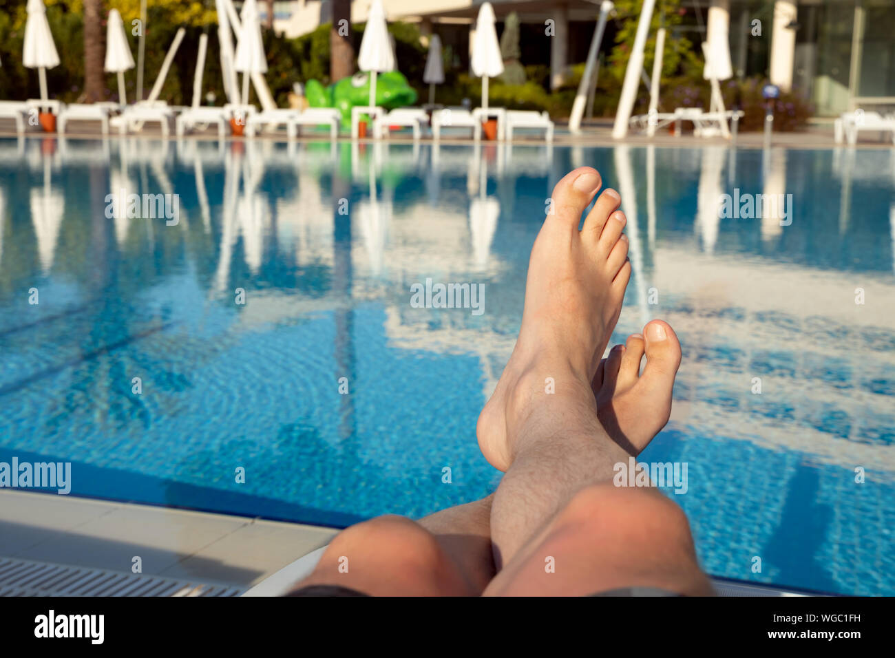 Gli uomini con i piedi sul background della piscina e rilassatevi in vacanza Foto Stock