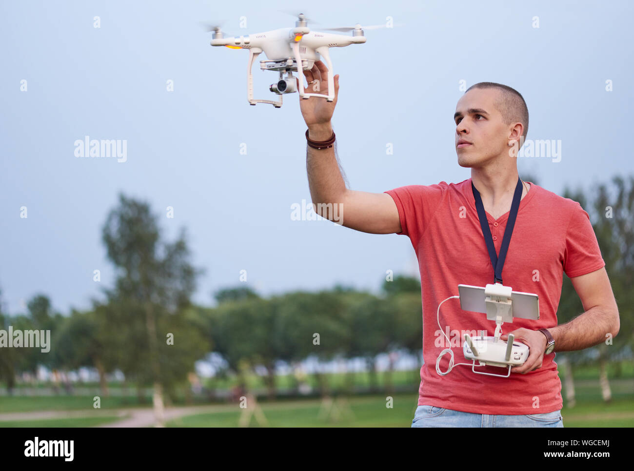 Giovane uomo l'impostazione di un quadrocopter nel parco. Foto Stock