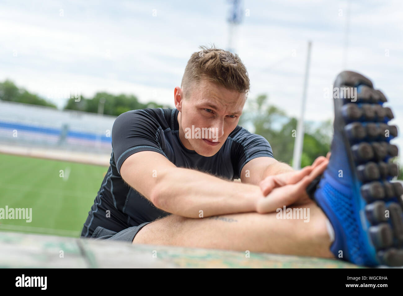 Immagine ravvicinata di giovane maschio sprinter stiramento sulla prima di una gara di Stadium. Foto Stock