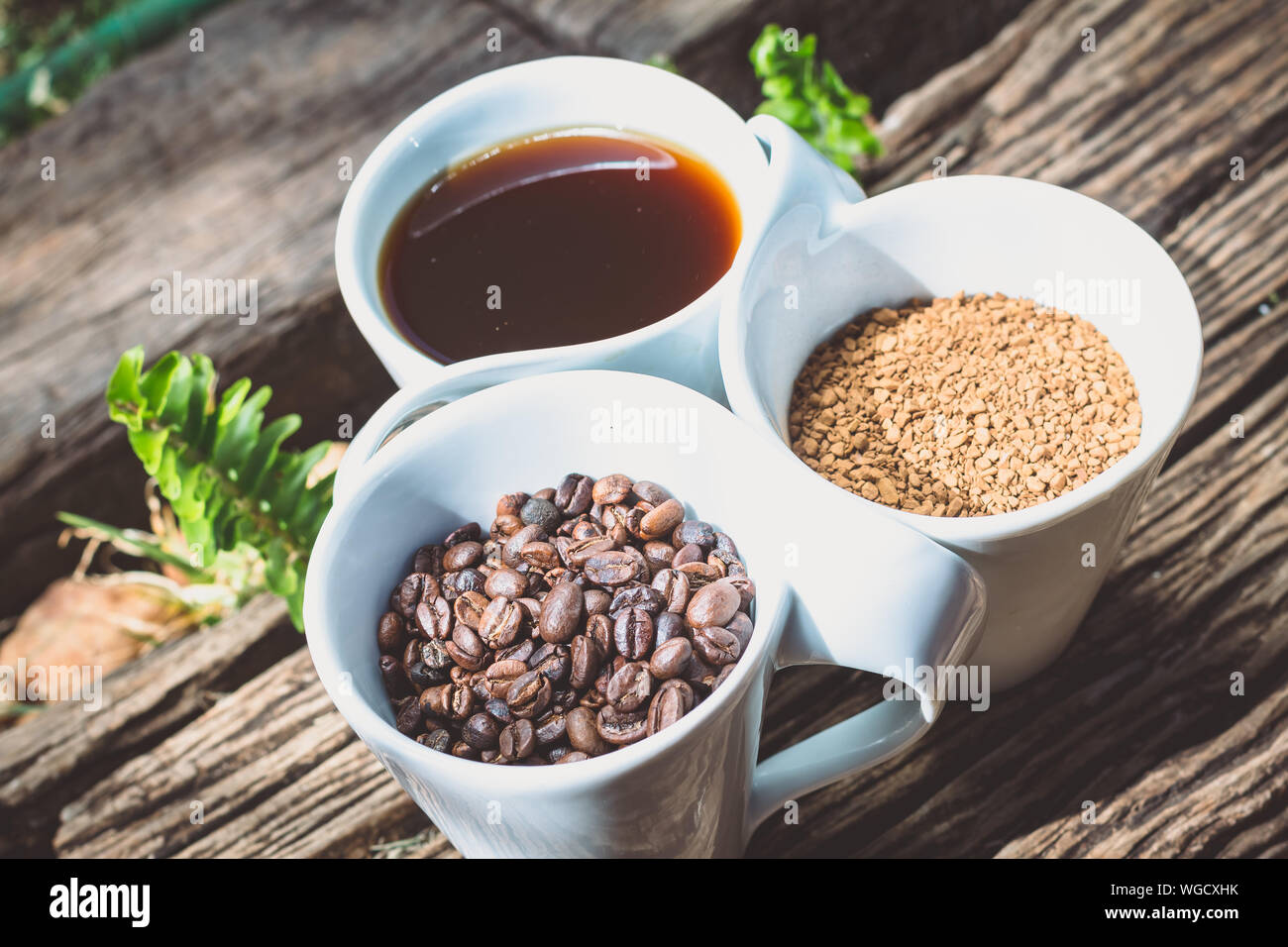 Close-up della tazza di caffè con fagioli arrosto e caffeina in tazze su legno Foto Stock