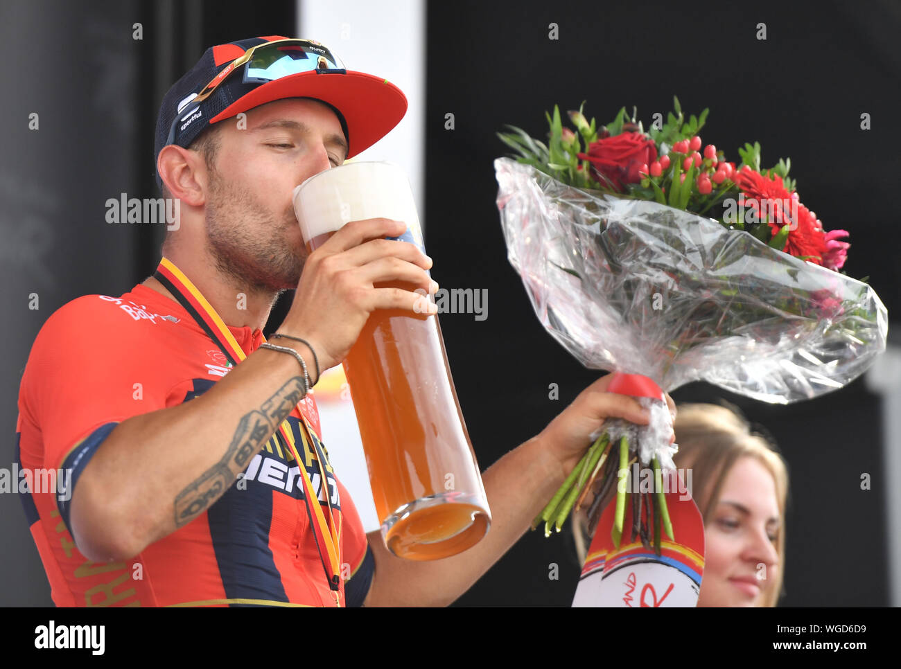 Erfurt, Germania. 01 Sep, 2019. Escursioni in bicicletta: UCI Europaserie - Germania Tour, fase 4, Eisenach - Erfurt (159, 50 km). Italian Sonny Colbrelli da Team Bahrain-Merida allieta la sua vittoria di tappa sul podio con un sorso di birra. Credito: Bernd Thissen/dpa/Alamy Live News Foto Stock