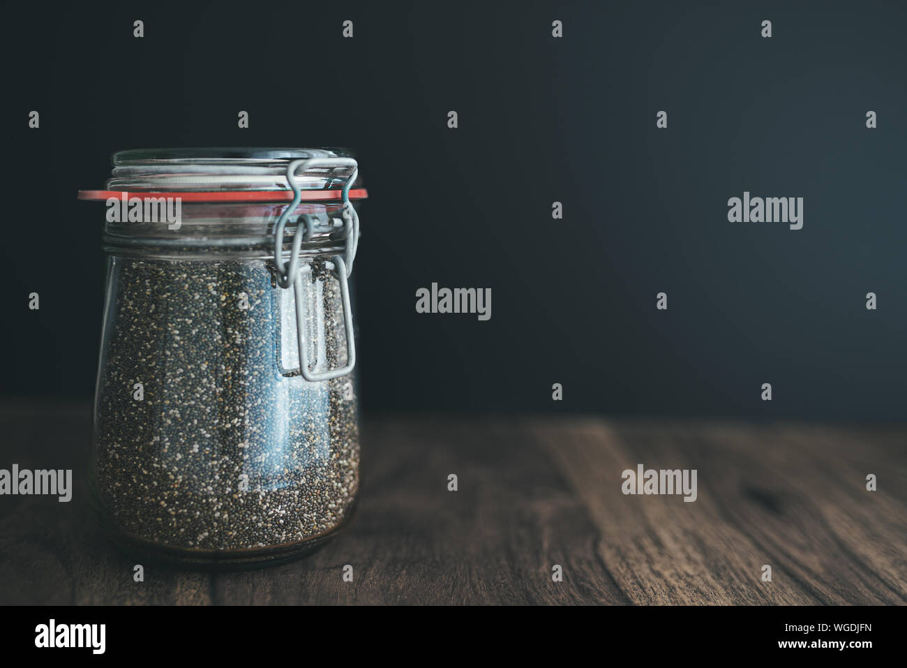 Close-up shot di chia semi in vetro weck jar sul tavolo di legno contro uno sfondo scuro Foto Stock