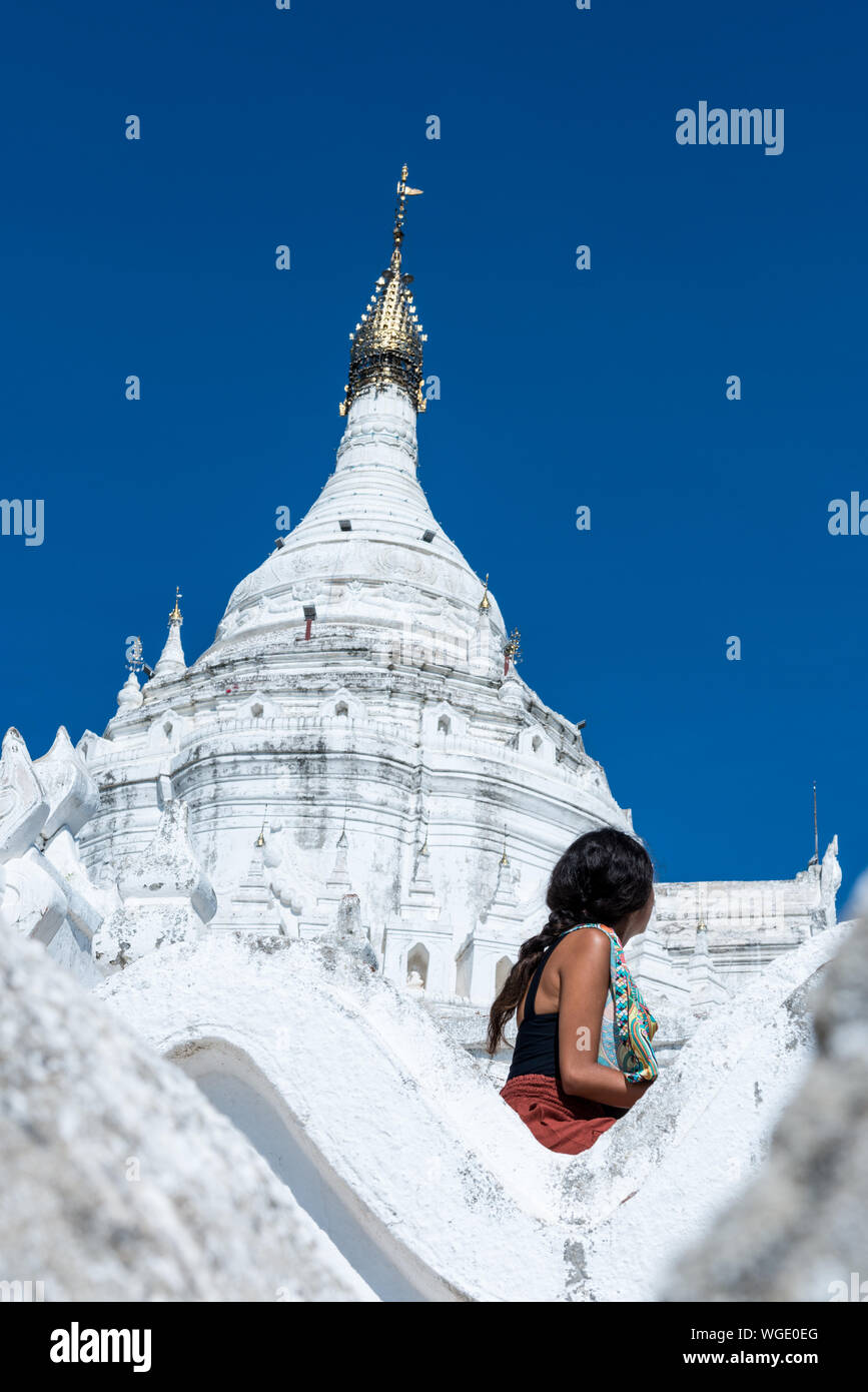 Immagine verticale della giovane ragazza guardando Pagoda Hsinbyume, un famoso tempio buddista dipinte di bianco, situato vicino a Mandalay, Myanmar Foto Stock
