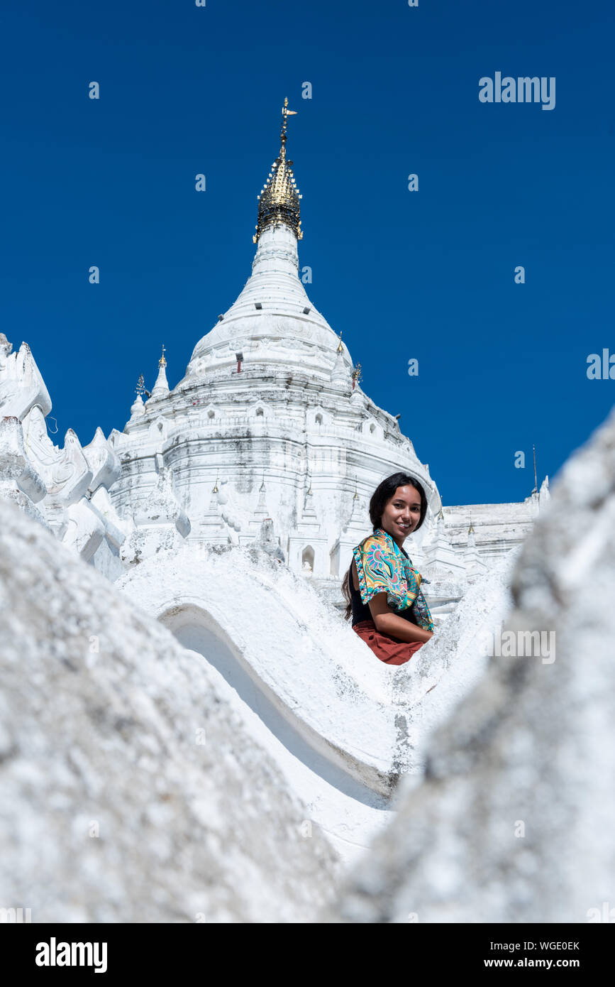 Immagine verticale dei giovani turisti sorridente alla Pagoda Hsinbyume, un famoso tempio buddista dipinte di bianco, situato vicino a Mandalay, Myanmar Foto Stock