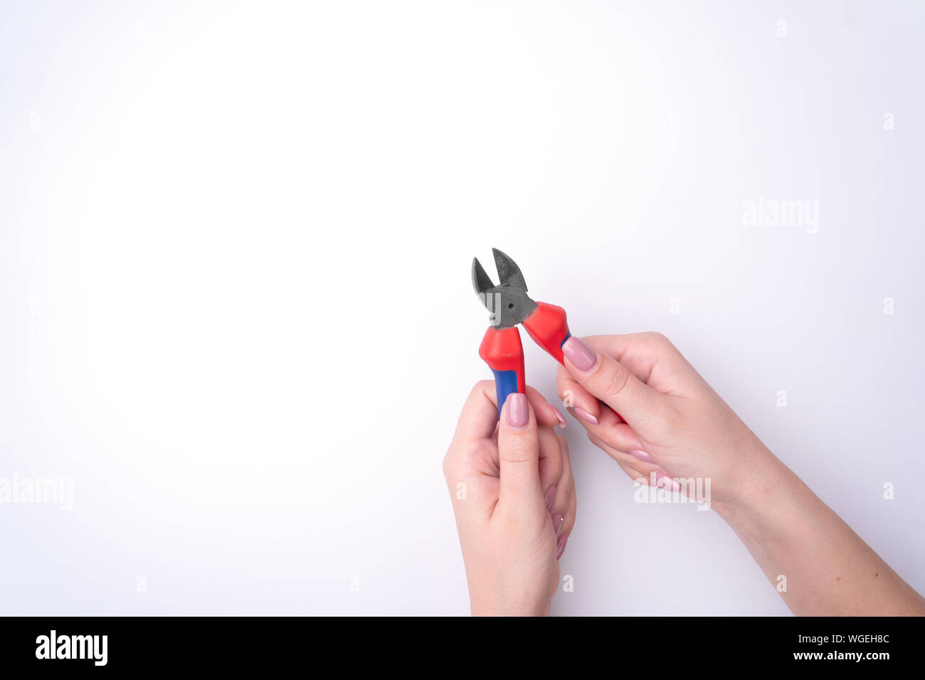 La moda donna di mano con una delicata manicure detiene un attrezzo. Di sicuro il lavoro, posto per un'iscrizione. Vista da sopra. Sfondo bianco, ombra contrastanti. Foto Stock
