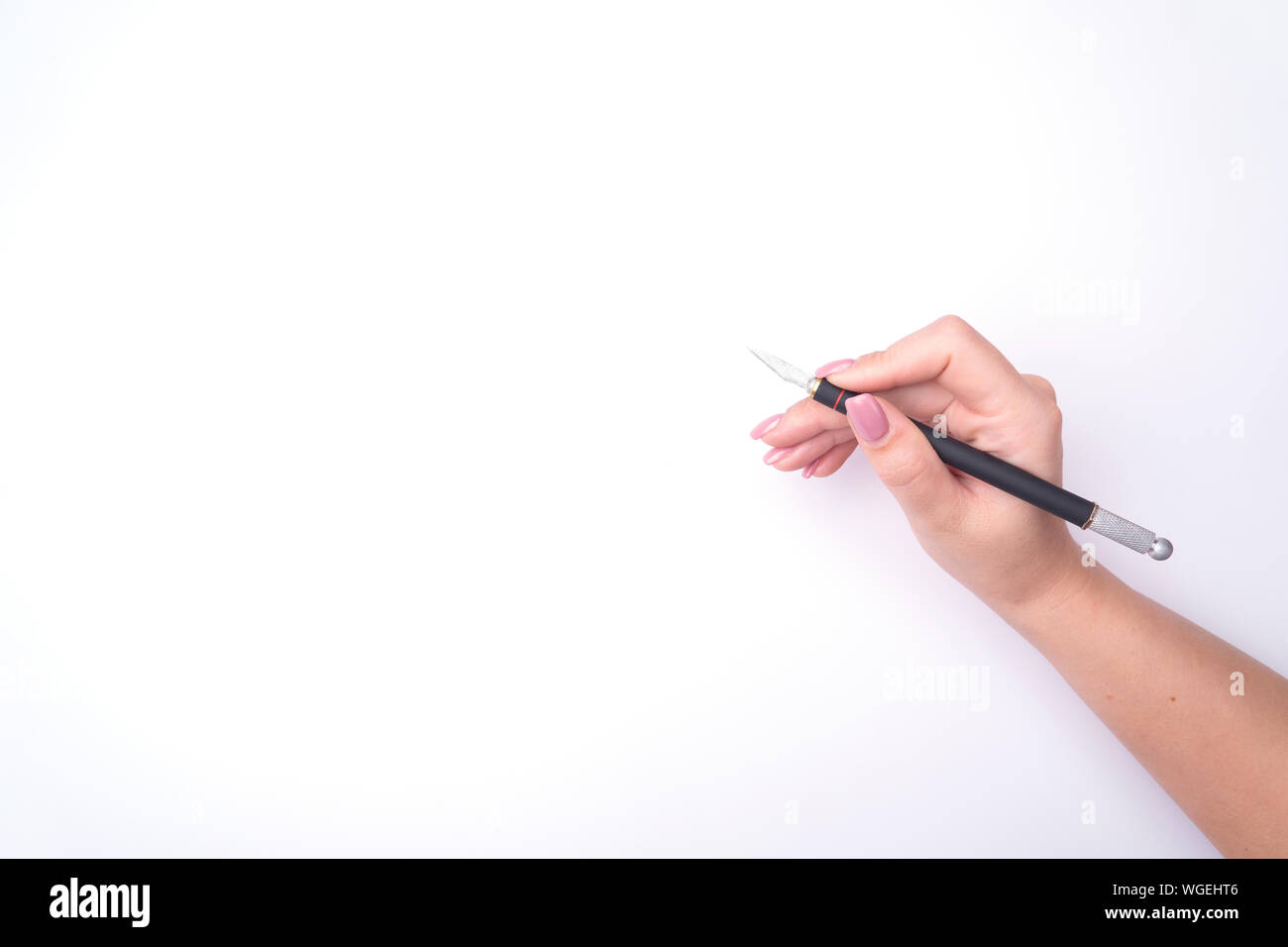 La moda donna di mano con una delicata manicure detiene un attrezzo. Di sicuro il lavoro, posto per un'iscrizione. Vista da sopra. Sfondo bianco, ombra contrastanti. Foto Stock